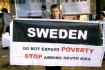 Bild på aktivist med banderoll ”Sverige – exportera inte fattigdom. Sluta att rusta upp Asien.”